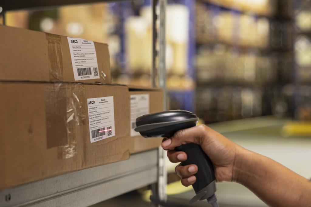 close up of black woman worker scanning packages in a large storehouse